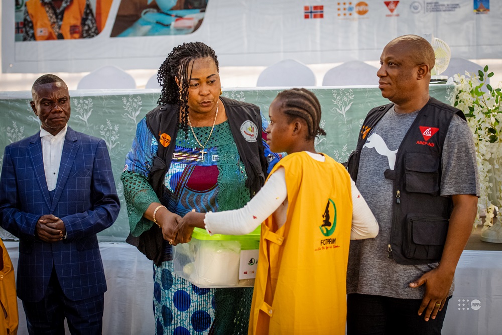 Mme Lyly Mujinga déléguée du ministre de la jeunesse et éveil patriotique remettant un kit à une bénéficiaire