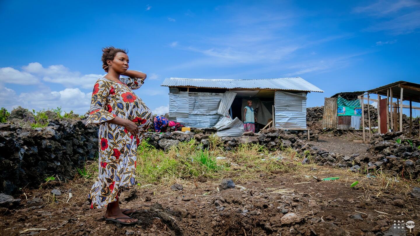 Ombeni Mburano, enceinte de sept mois, devant les ruines d’un abri de fortune frappé par une bombe, dans un site informel de déplacés à l’ouest de Goma. © UNFPA RDC Jonas Yunus